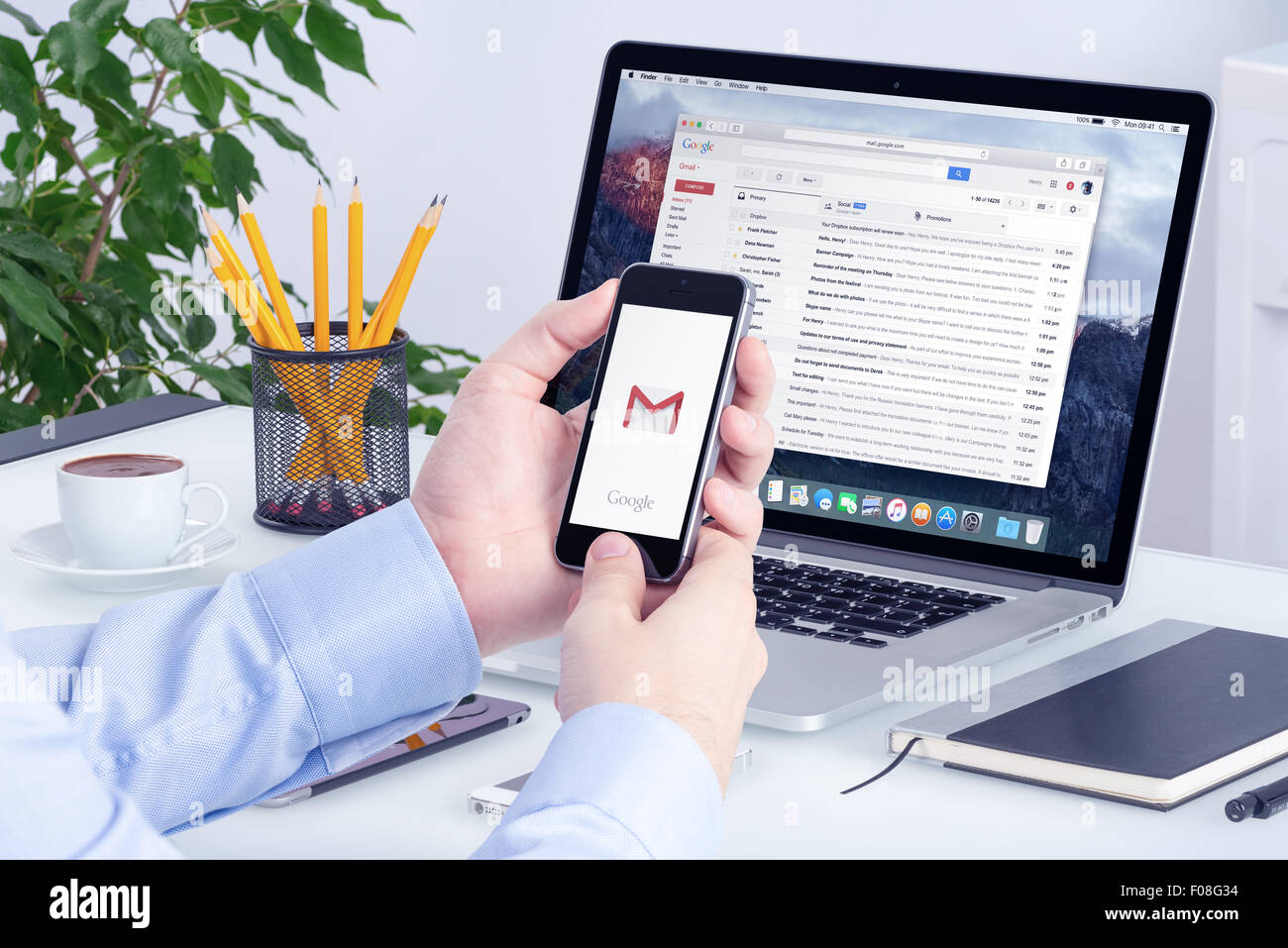 Varna, Bulgaria - May 29, 2015: Gmail app on the iPhone display in man hands and Gmail desktop version on the Macbook screen. Stock Photo