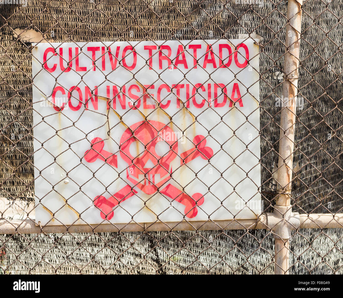Sign in Spanish on farm gate in Spain saying crop treated with insecticide ( cultivo tratado con insecticida ). Stock Photo