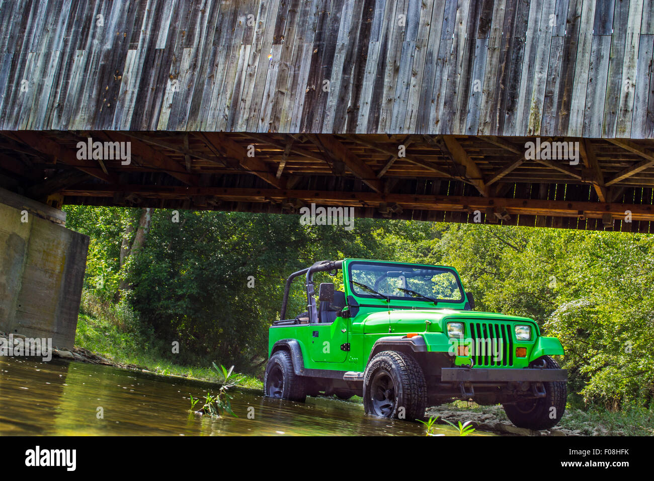 green 93 jeep wrangler in creek water under cabin creek bridge in lewis county, tollesboro kentucky Stock Photo