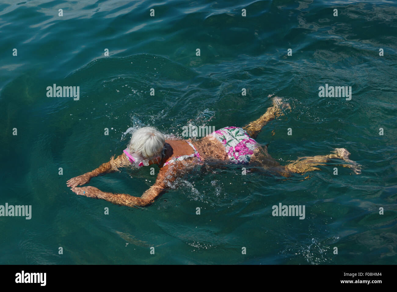 High angle view of senior woman that swimming with goggles in the sea. Stock Photo