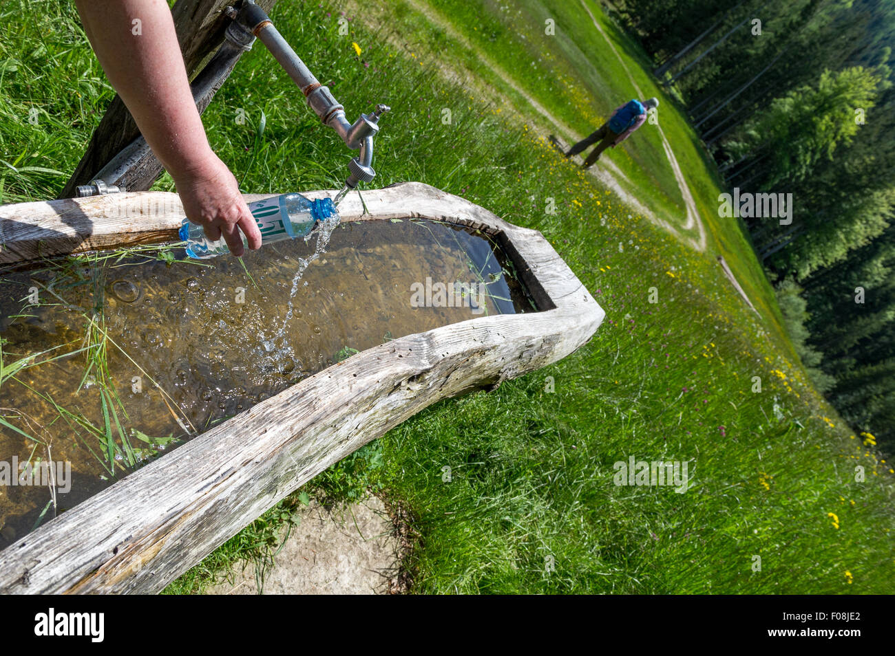 Filling plastic water bottle from a tap fed from a mountain stream in the Austrian Mountains. Stock Photo