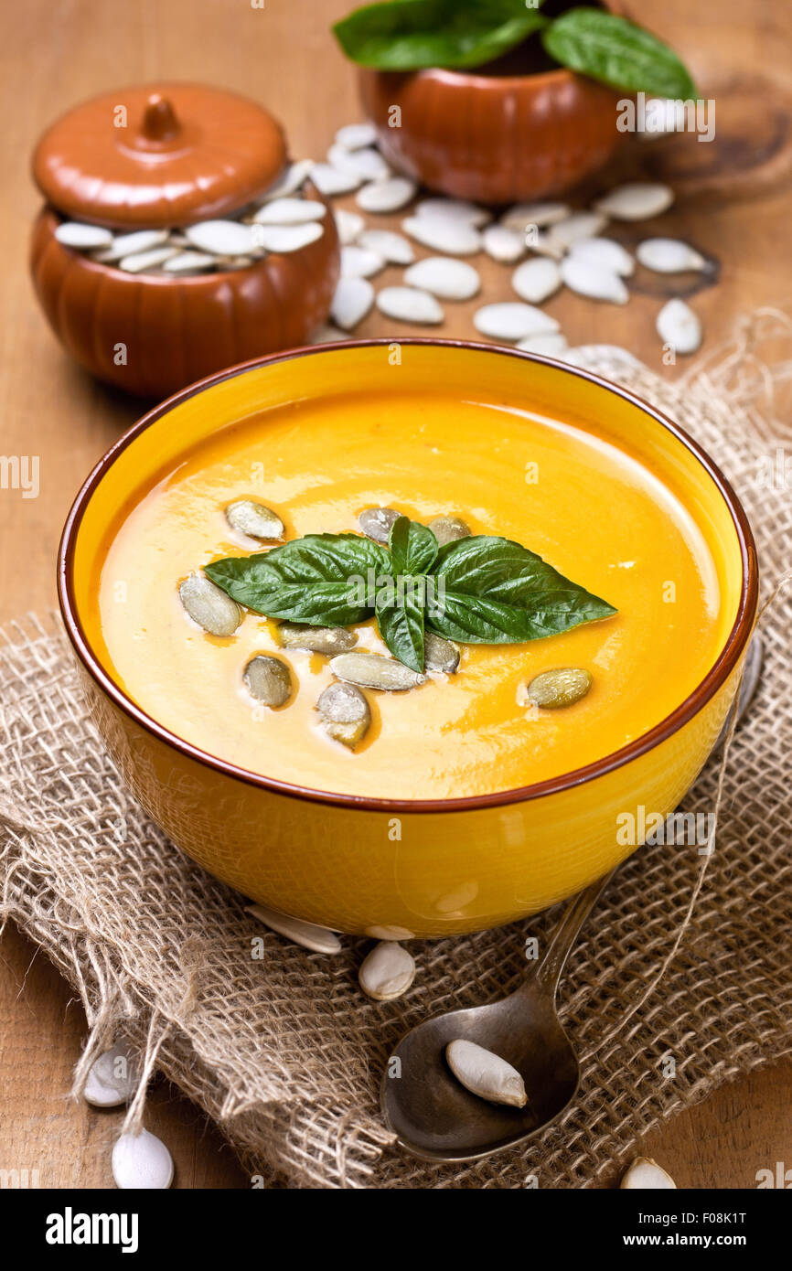 pumpkin soup - puree and basil in a white bowl on a wooden background Stock Photo