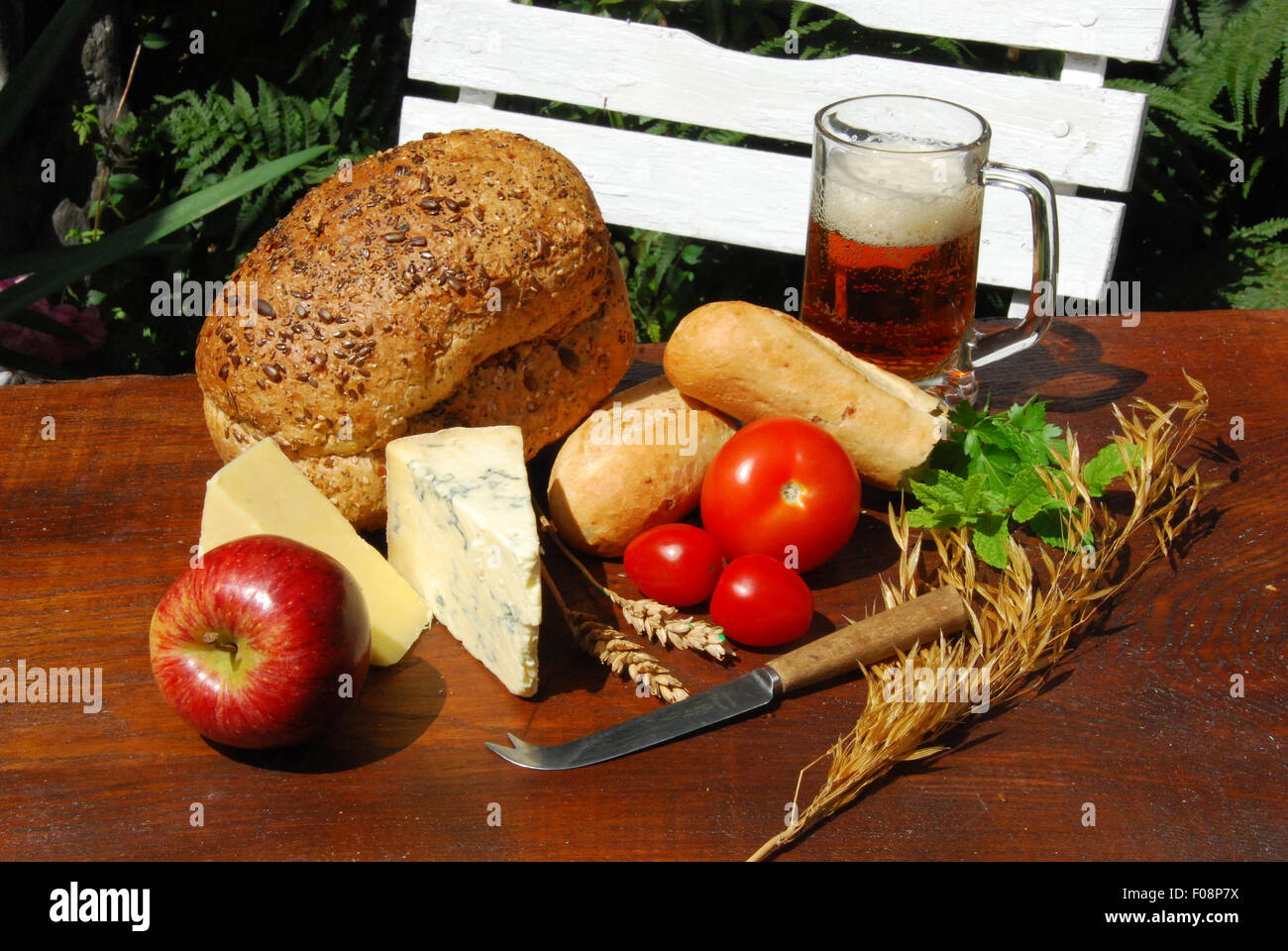 PLOUGHMAN'S LUNCH. A pub garden setting of a farmers lunch, with fresh bread,cheese,apple,tomato and real ale beer Stock Photo