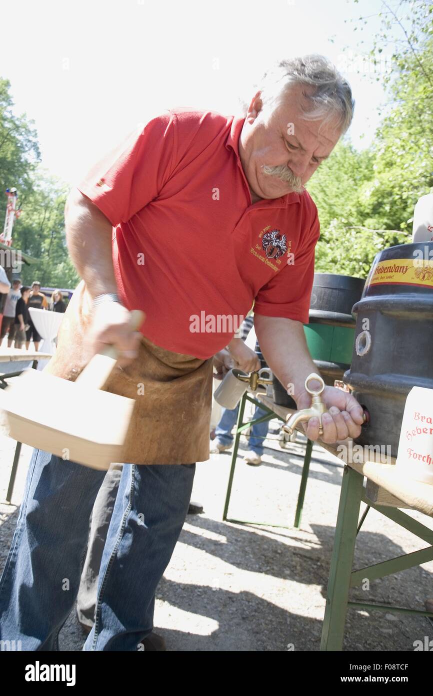 Senior man fitting tap in wine barrel in Franconian Switzerland, Bavaria, Germany Stock Photo