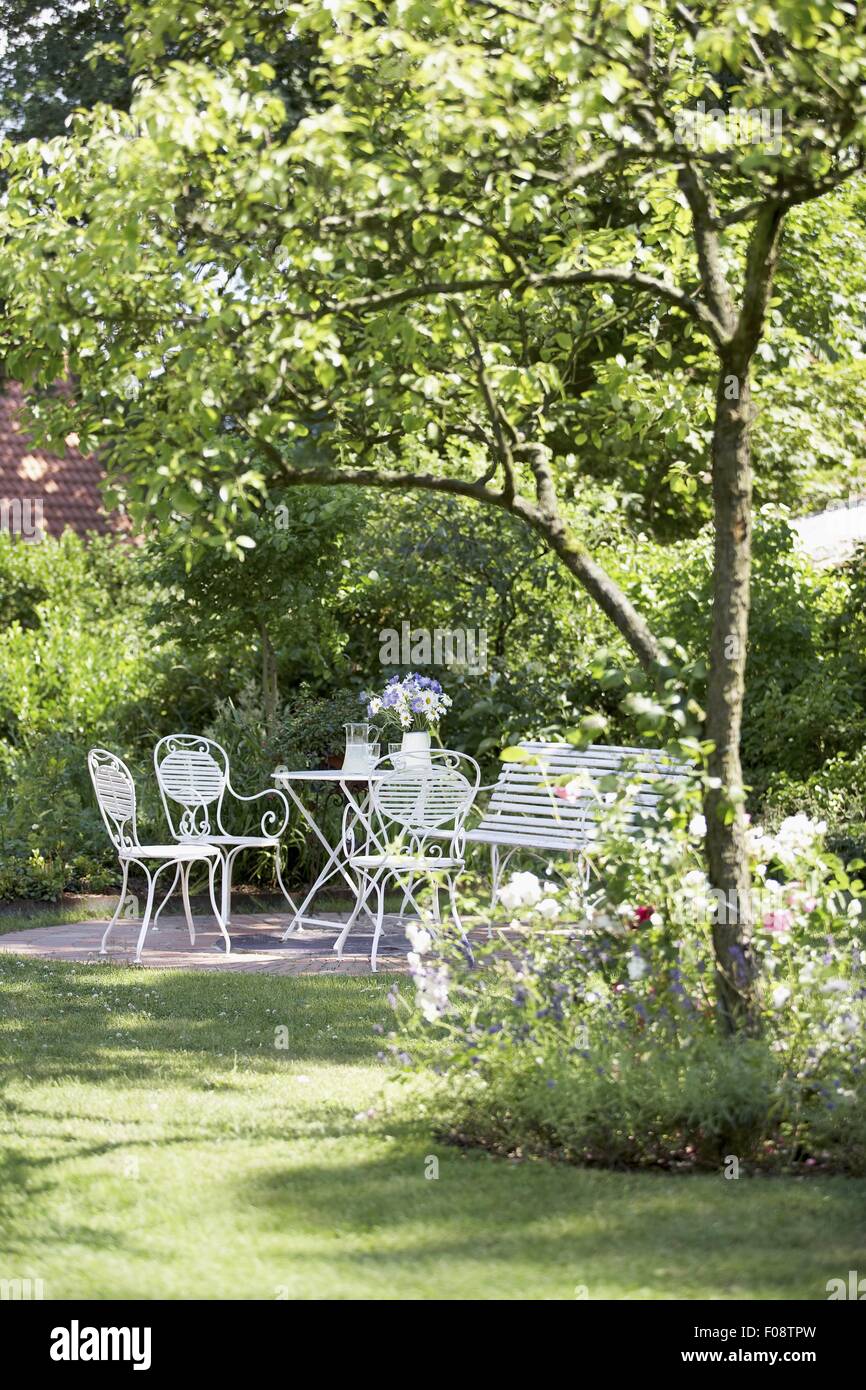 Garden space with bistro furniture under shade of wild cherry tree Stock Photo