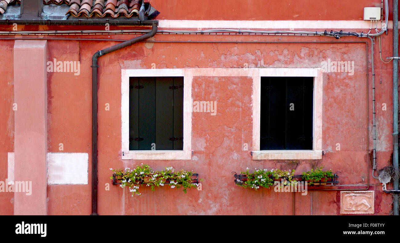 two windows and drained pipe with coral color wall house building in Venice, Italy Stock Photo