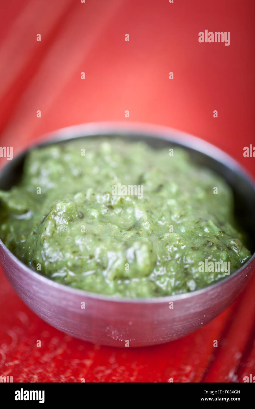 Bowl of Indian corriander chutney on a red table Stock Photo