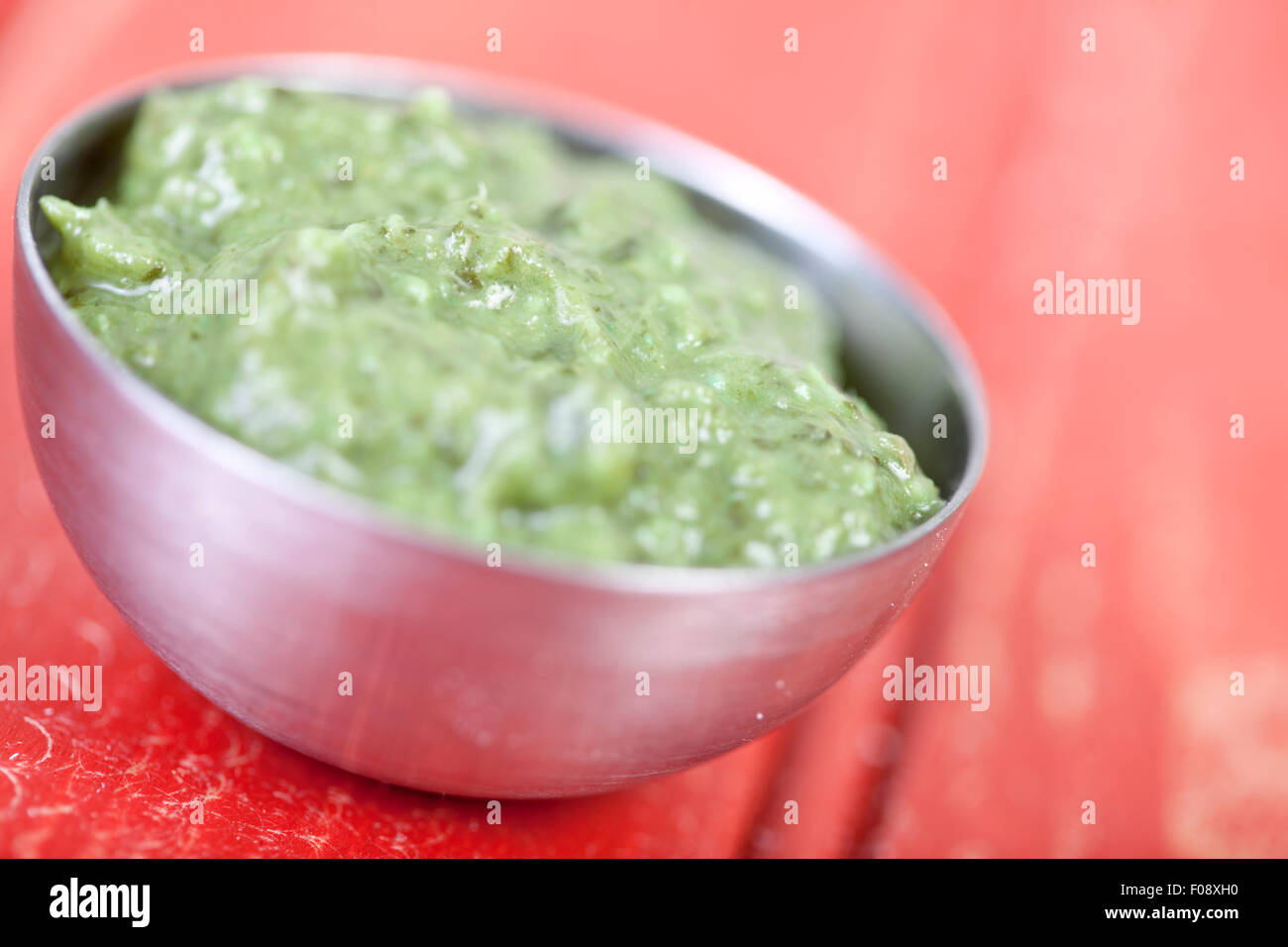Bowl of Indian corriander chutney on a red table Stock Photo