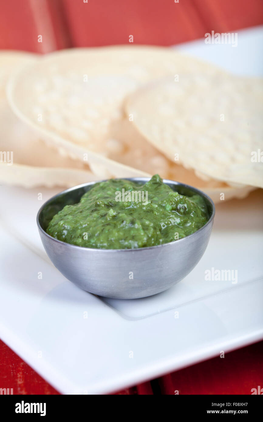 A pile of poppadoms with a bowl of corriander chutney Stock Photo