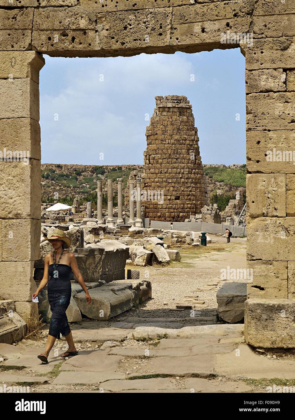 Woman walking through gate with ruins in background, Perge, Turkey Stock Photo