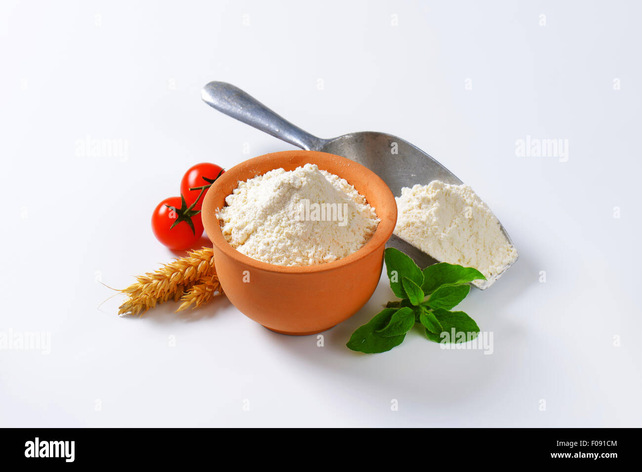 Finely ground flour in terracotta bowl and metal scoop Stock Photo