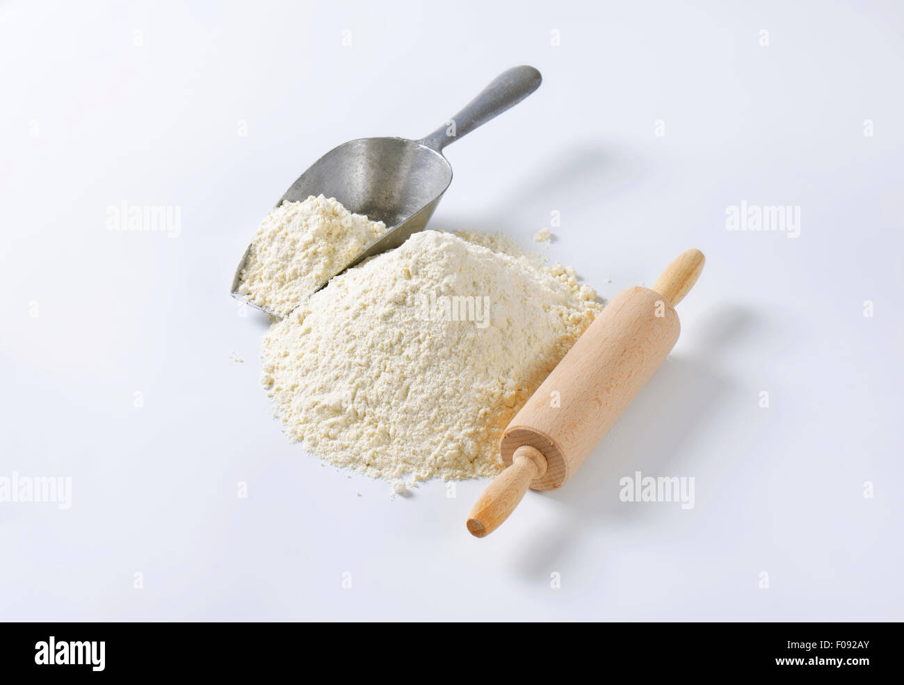 Pile of finely ground flour, wood rolling pin and metal scoop Stock Photo