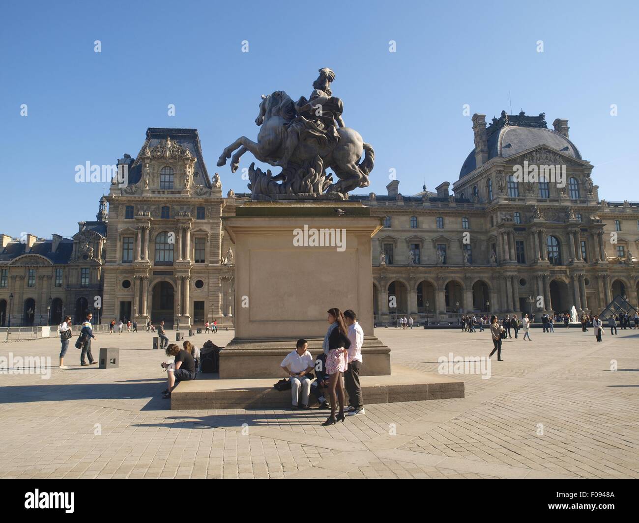 Facade of Louvre facade and tourist near statue in Paris, France Stock