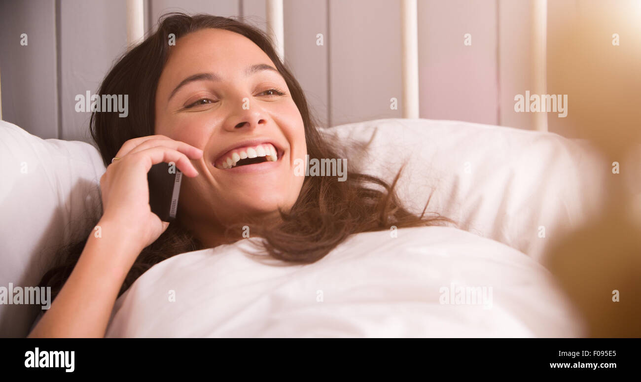 Woman Lying In Bed Having Conversation On Mobile Phone Stock Photo