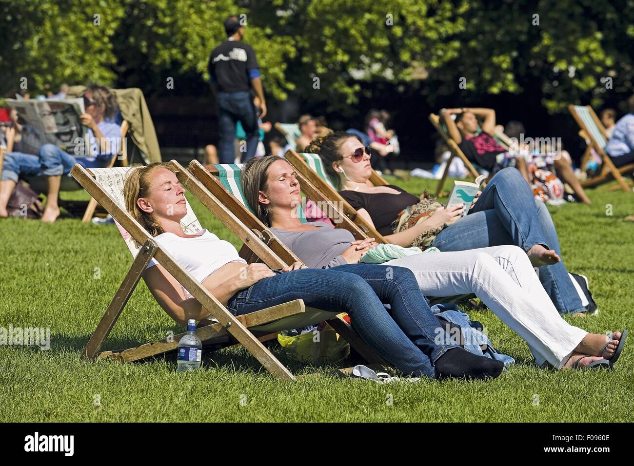People relaxing in deckchairs in Green Park, Westminster, London, UK