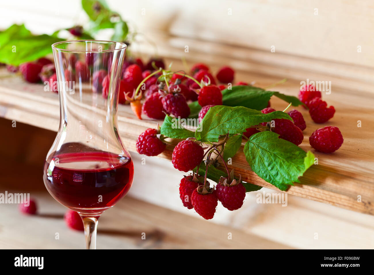 raspberry liqueur and ripe berries with leaves Stock Photo Alamy