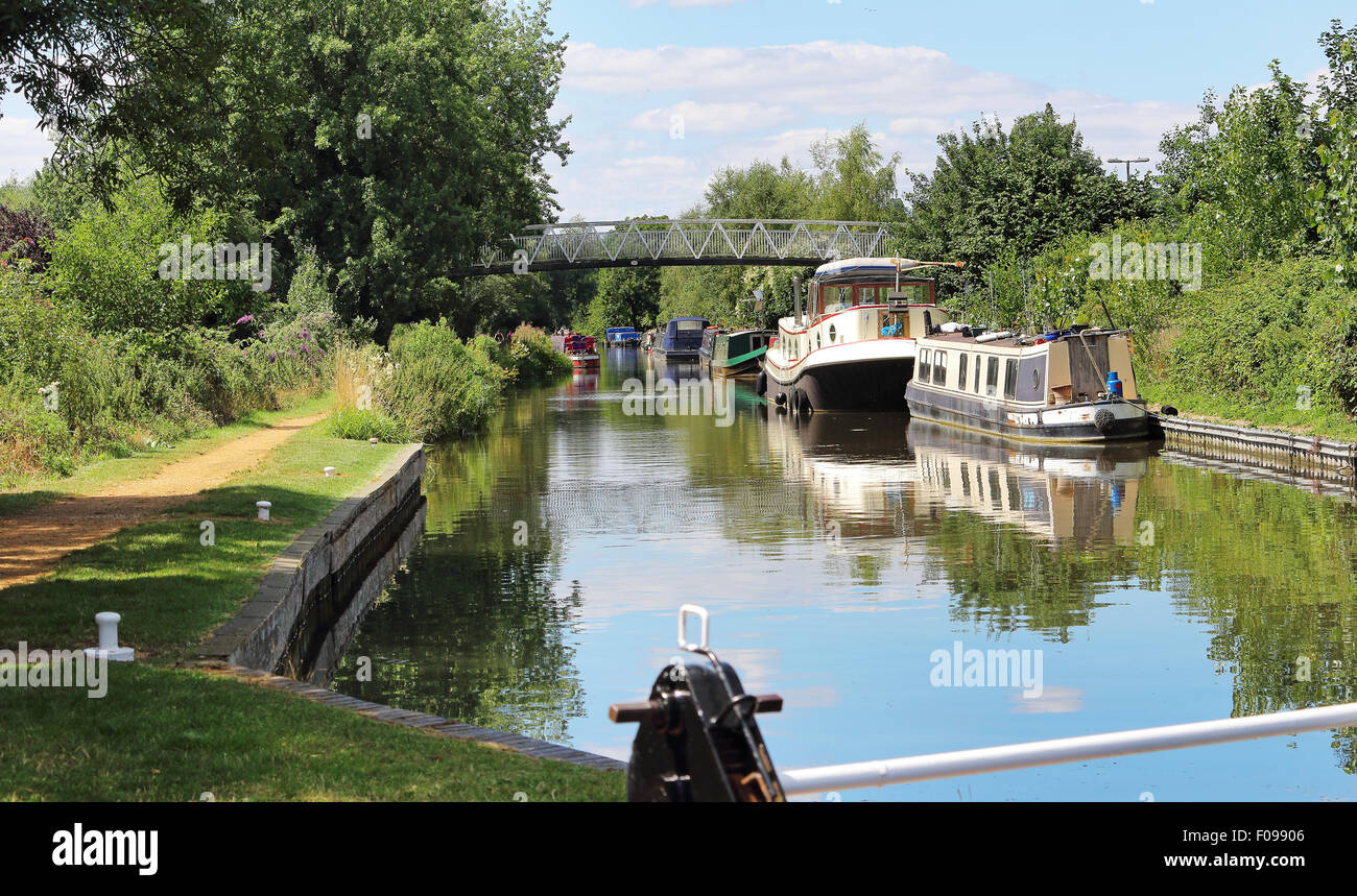 Narrowboats moored on the Kennett and Avon Canal in England with footbridge in the background Stock Photo