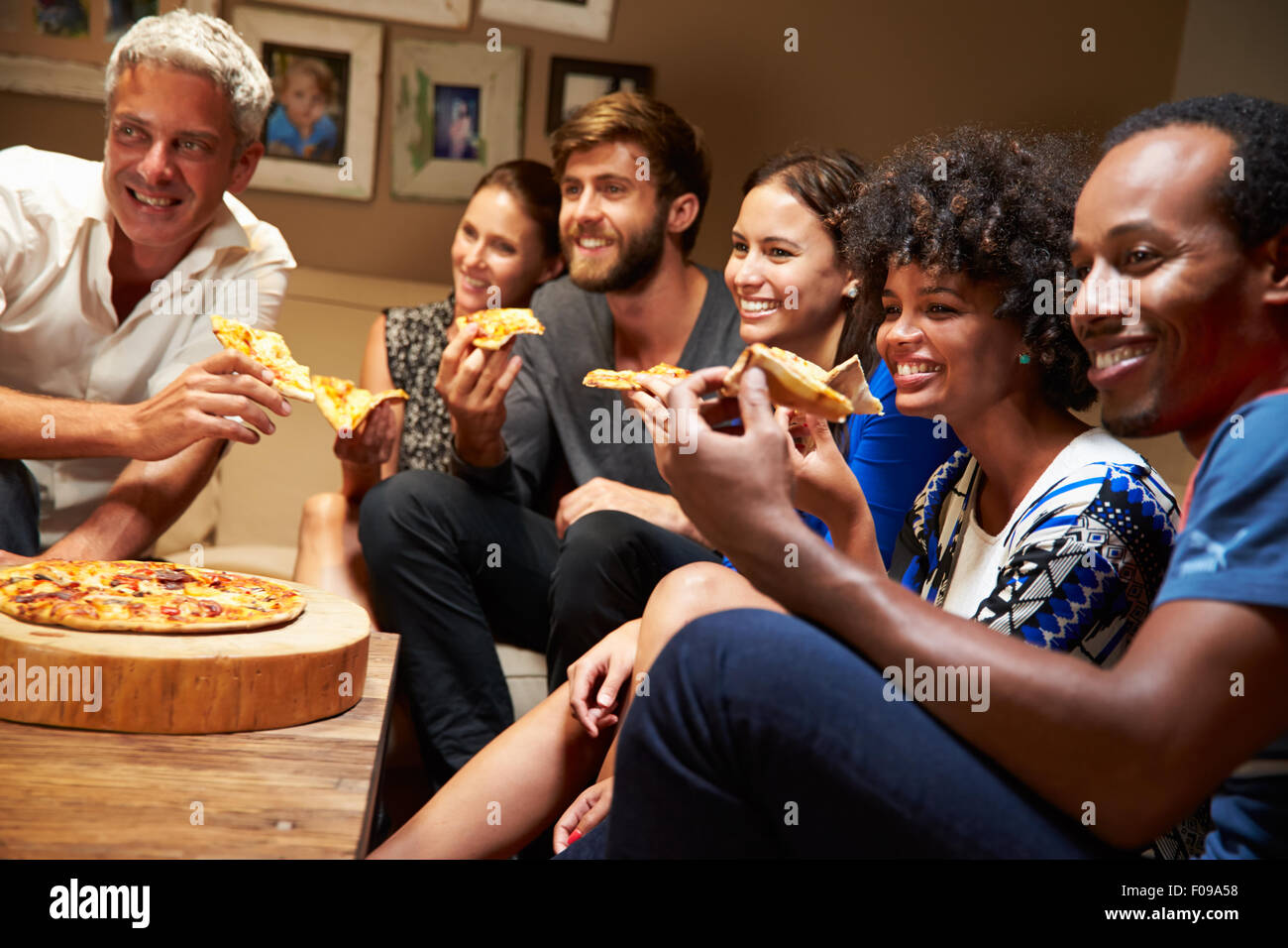 Friends eating pizza at a house party, watching television Stock Photo -  Alamy