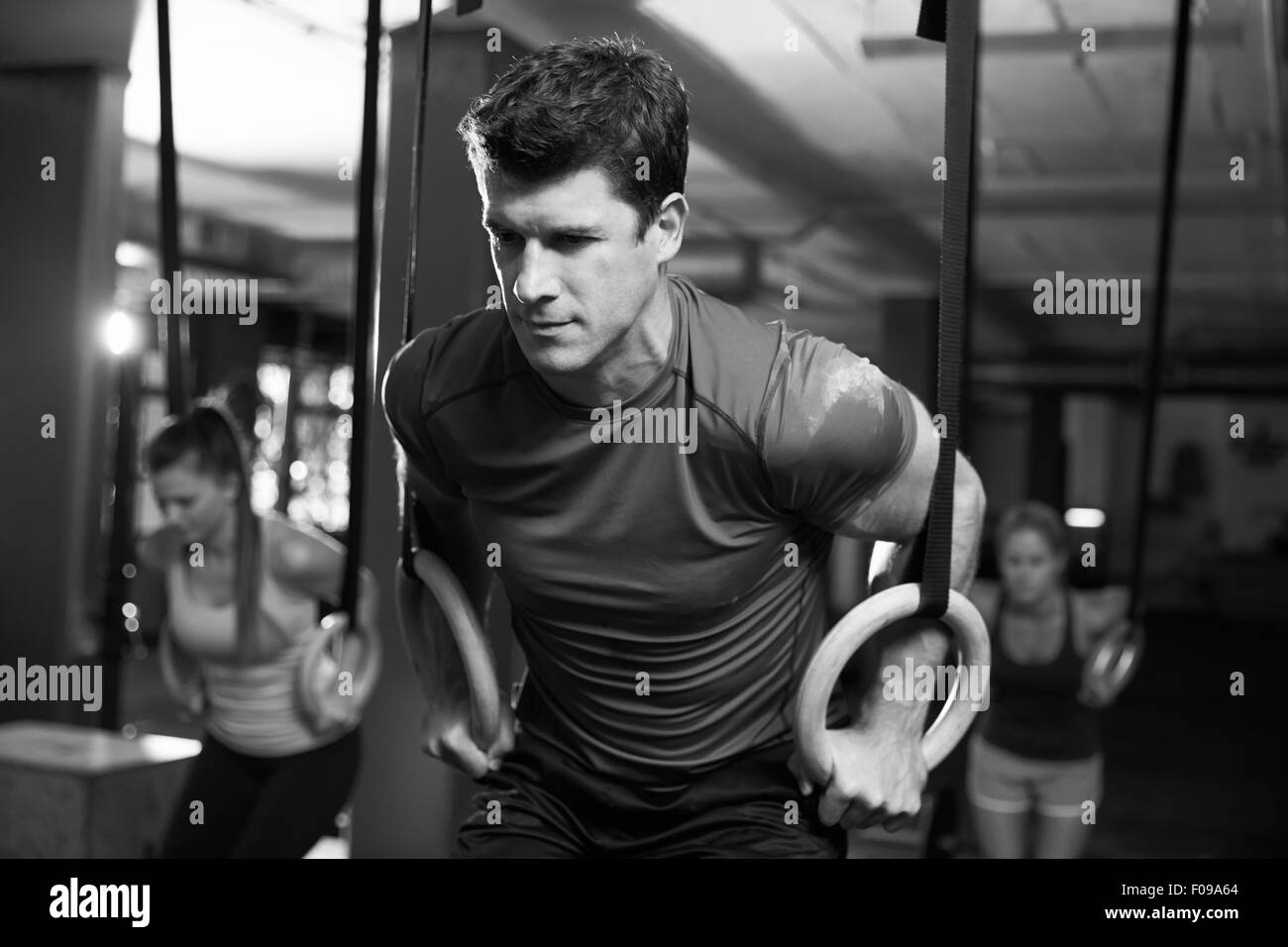 Black And White Shot Of Man Exercising With Gymnastic Rings Stock Photo