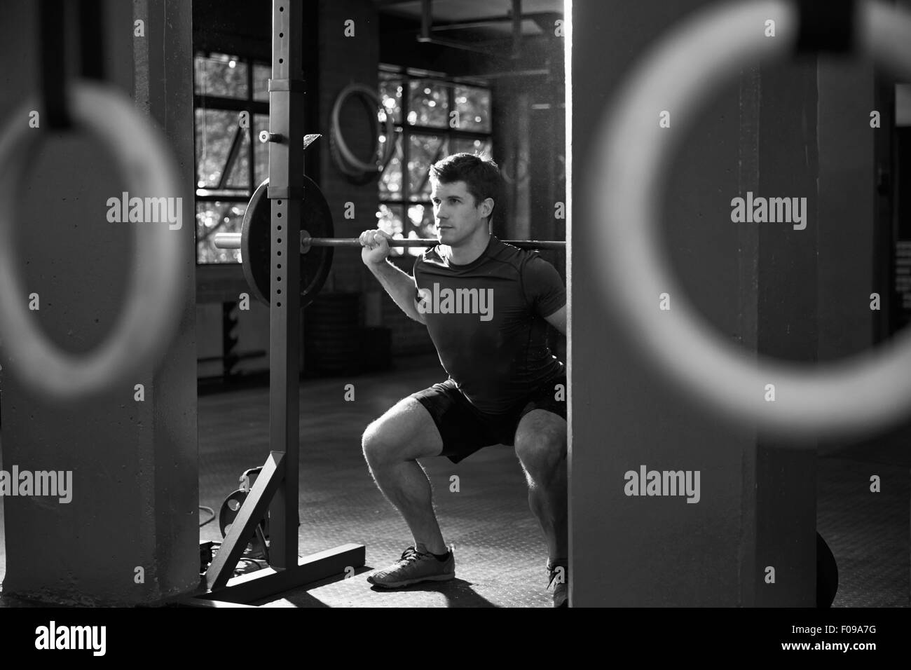 Black And White Shot Of Man Clean And Jerk Lifting Weights Stock Photo