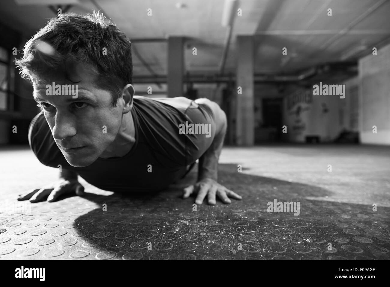 Black And White Shot Of Man In Gym Doing Press-Ups Stock Photo