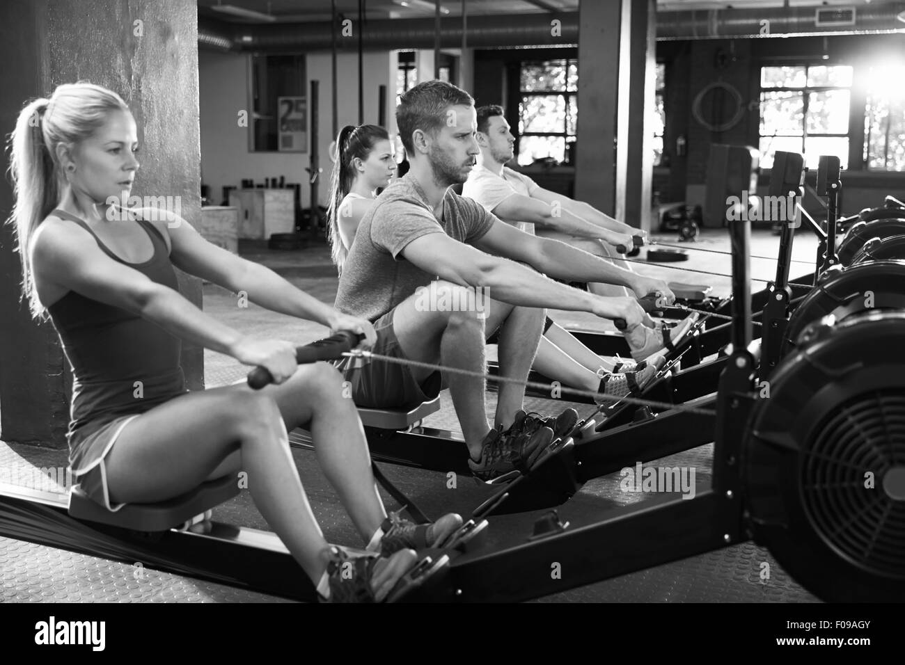 Black And White Shot Of Gym Class Using Rowing Machines Stock Photo