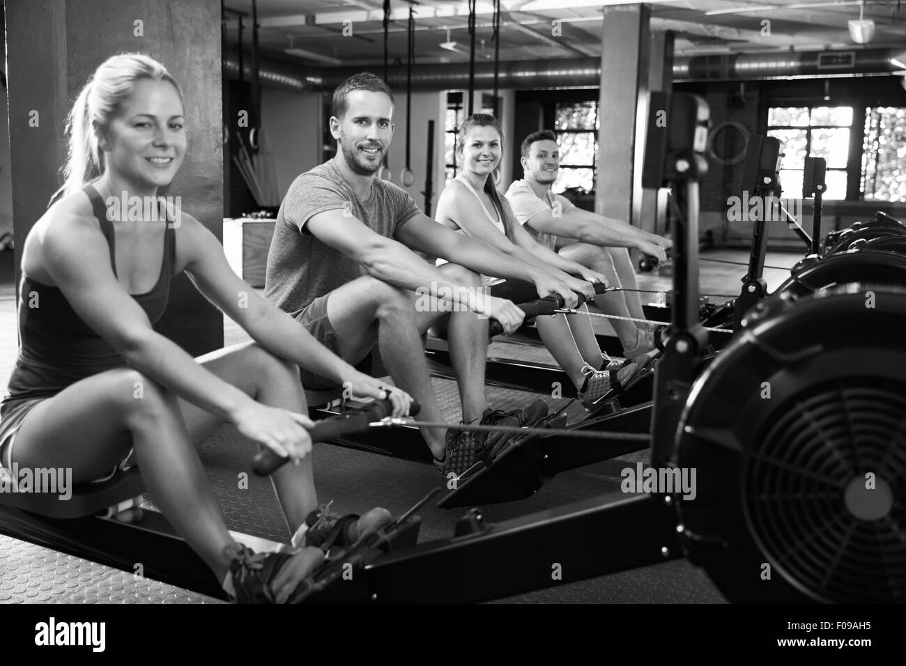 Black And White Shot Of Gym Class Using Rowing Machines Stock Photo