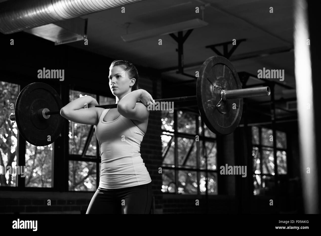 Black And White Shot Of Woman In Gym Lifting Weights Stock Photo