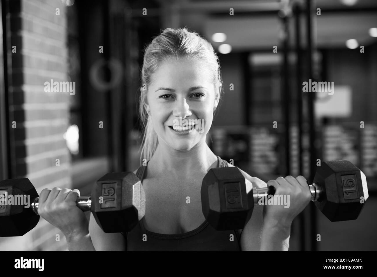 Black And White Shot Of Woman In Gym Lifting Hand Weights Stock Photo