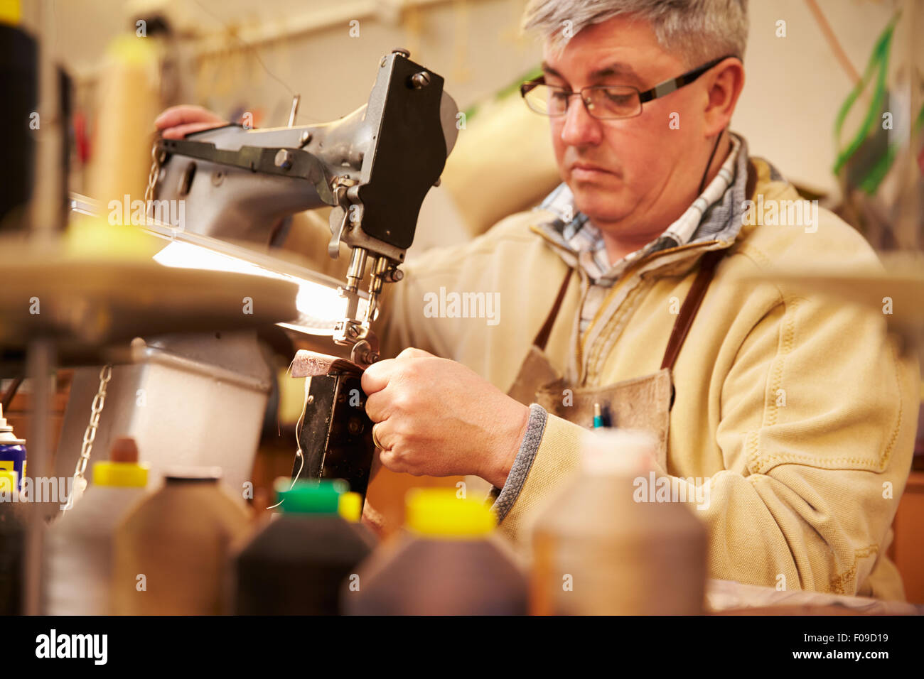 Shoemaker stitching leather in a workshop Stock Photo