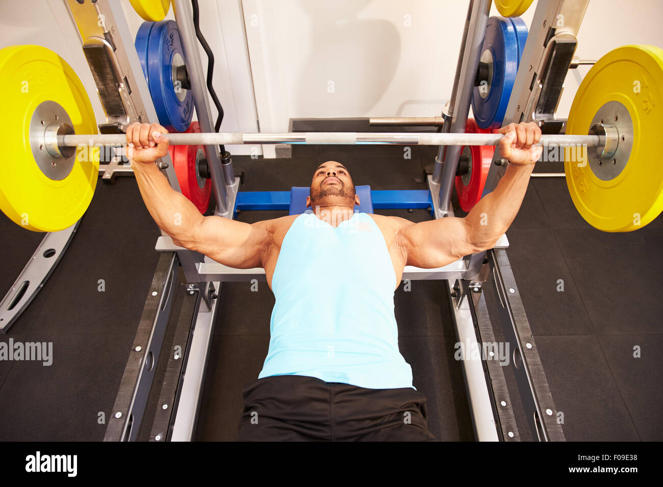 Man flexing muscles while bench pressing weights at a gym Stock Photo