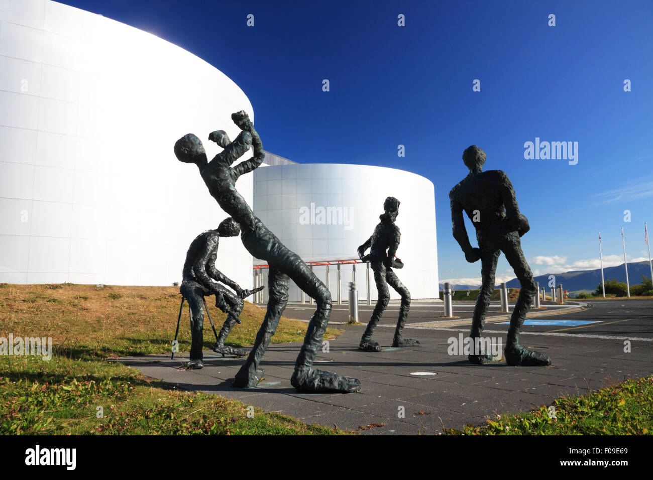 A group of bronze figures depicting musicians beside a group of metal storage tanks. Stock Photo