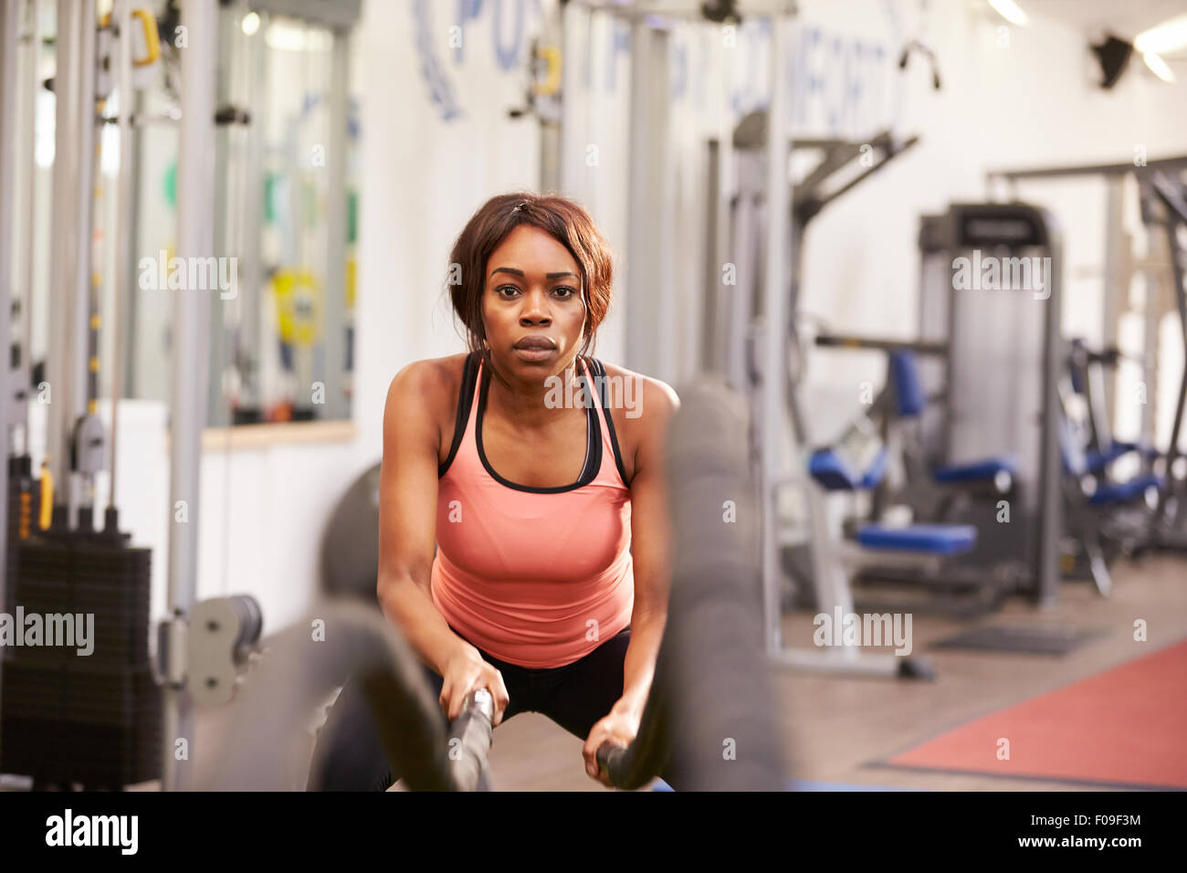 Young woman working out with battle ropes at a gym Stock Photo