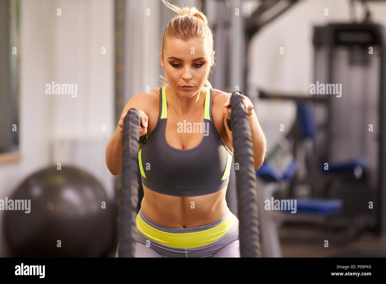 Young woman preparing to work out with battle ropes at a gym Stock Photo