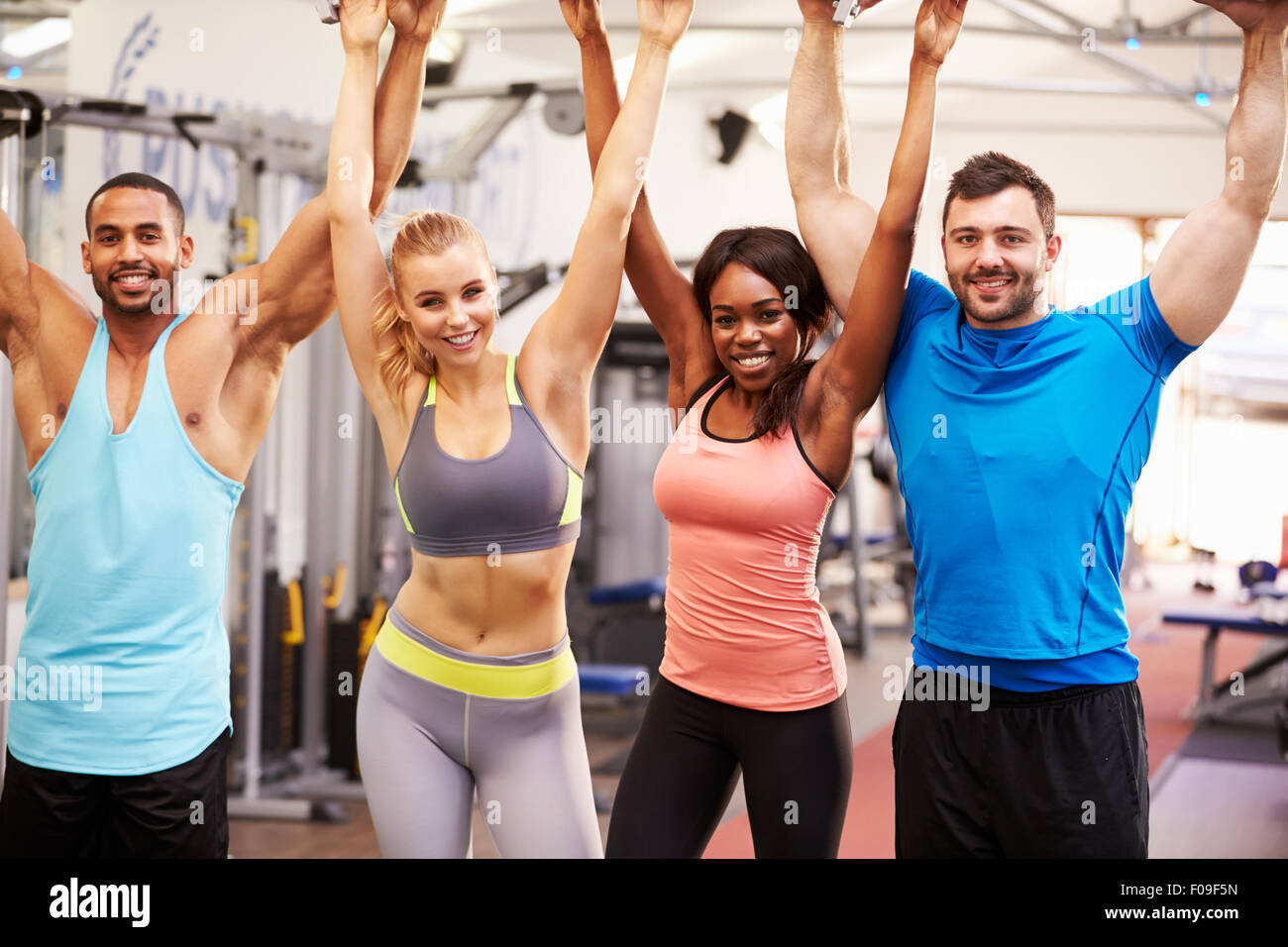 Happy, healthy group of people with arms in the air at a gym Stock Photo