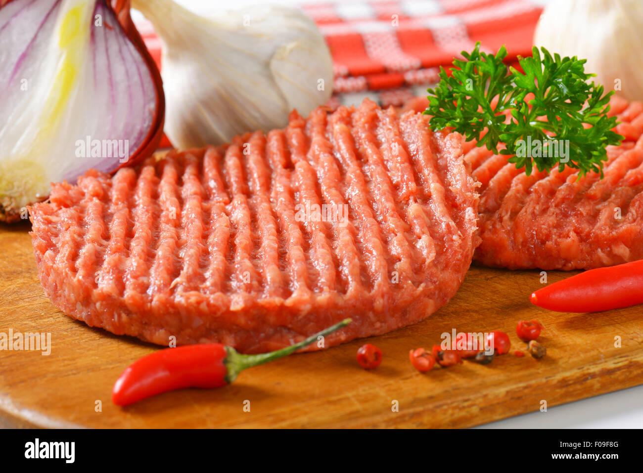 raw hamburger patties and vegetables on cutting board Stock Photo Alamy
