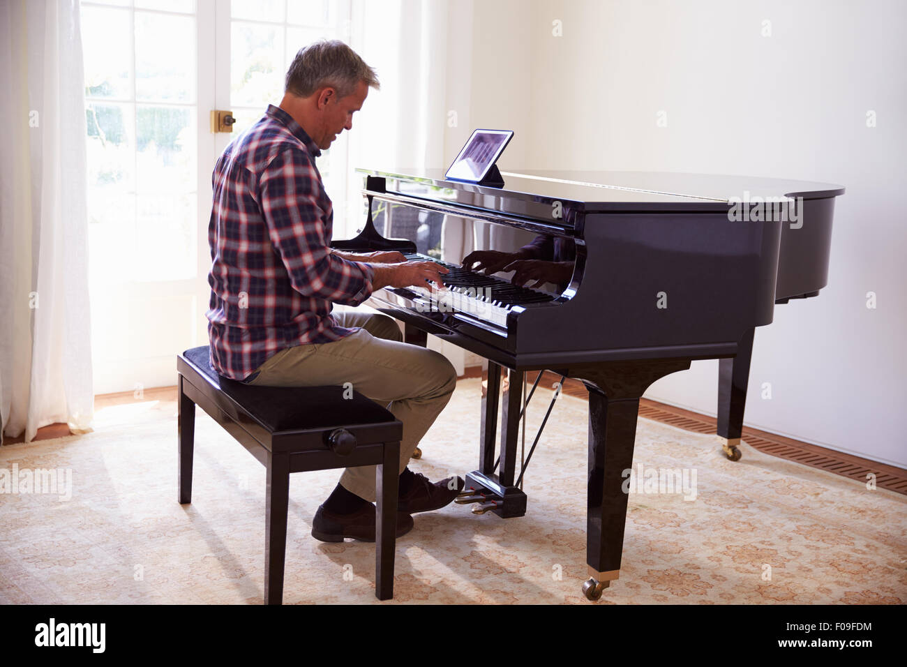 Man Learning To Play Piano Using Digital Tablet Application Stock Photo -  Alamy