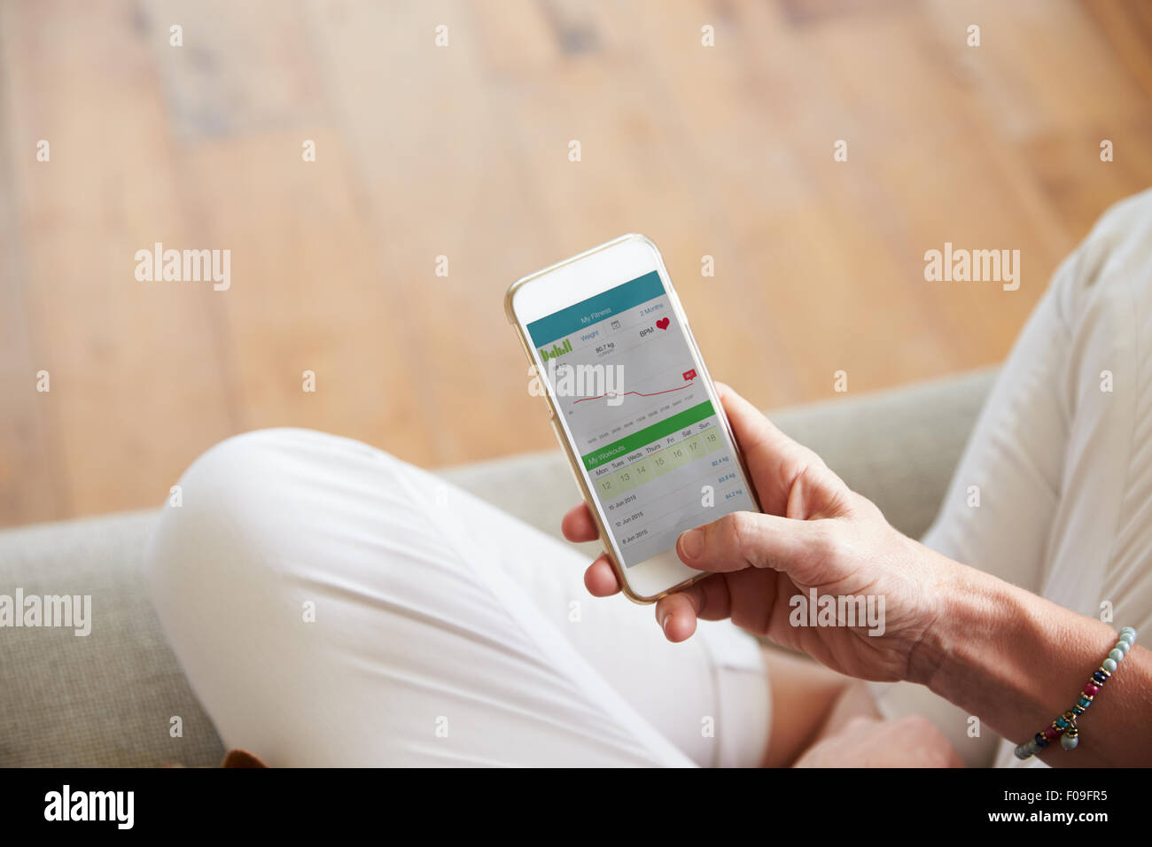 Woman Looking At Health Monitoring App On Smartphone Stock Photo