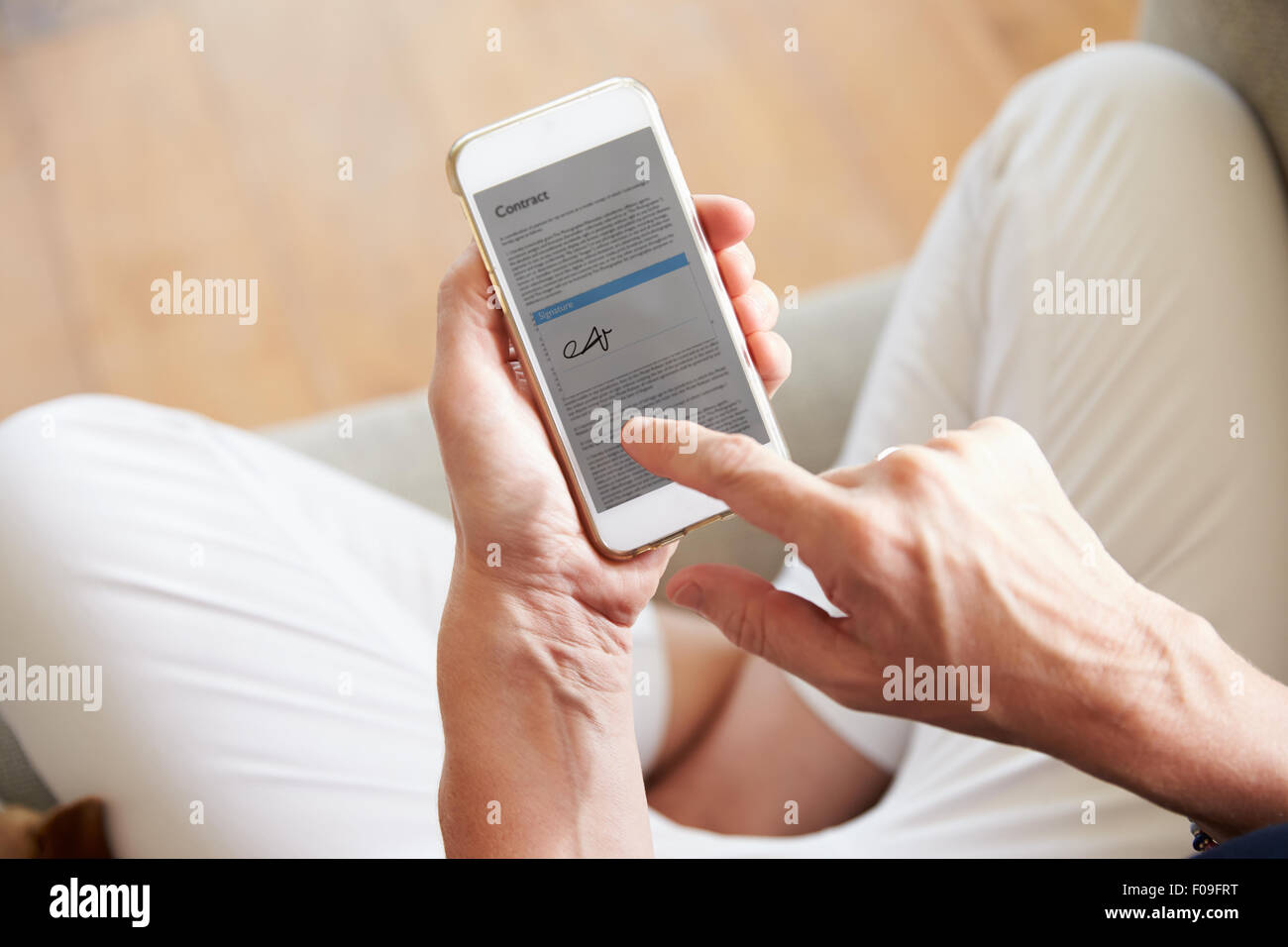 Woman Signing Contract On Smartphone At Home Stock Photo