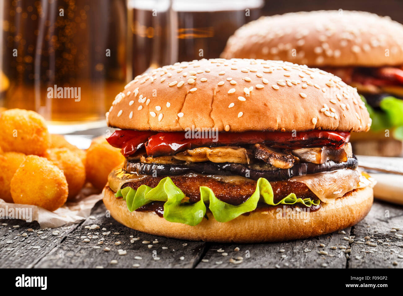 Delicious burgers with fried potato balls and beer on a rustic table Stock Photo