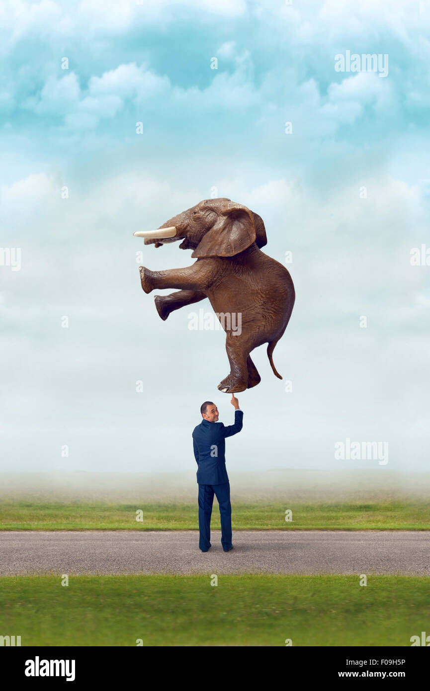 business strength concept businessman holding an elephant with one finger Stock Photo