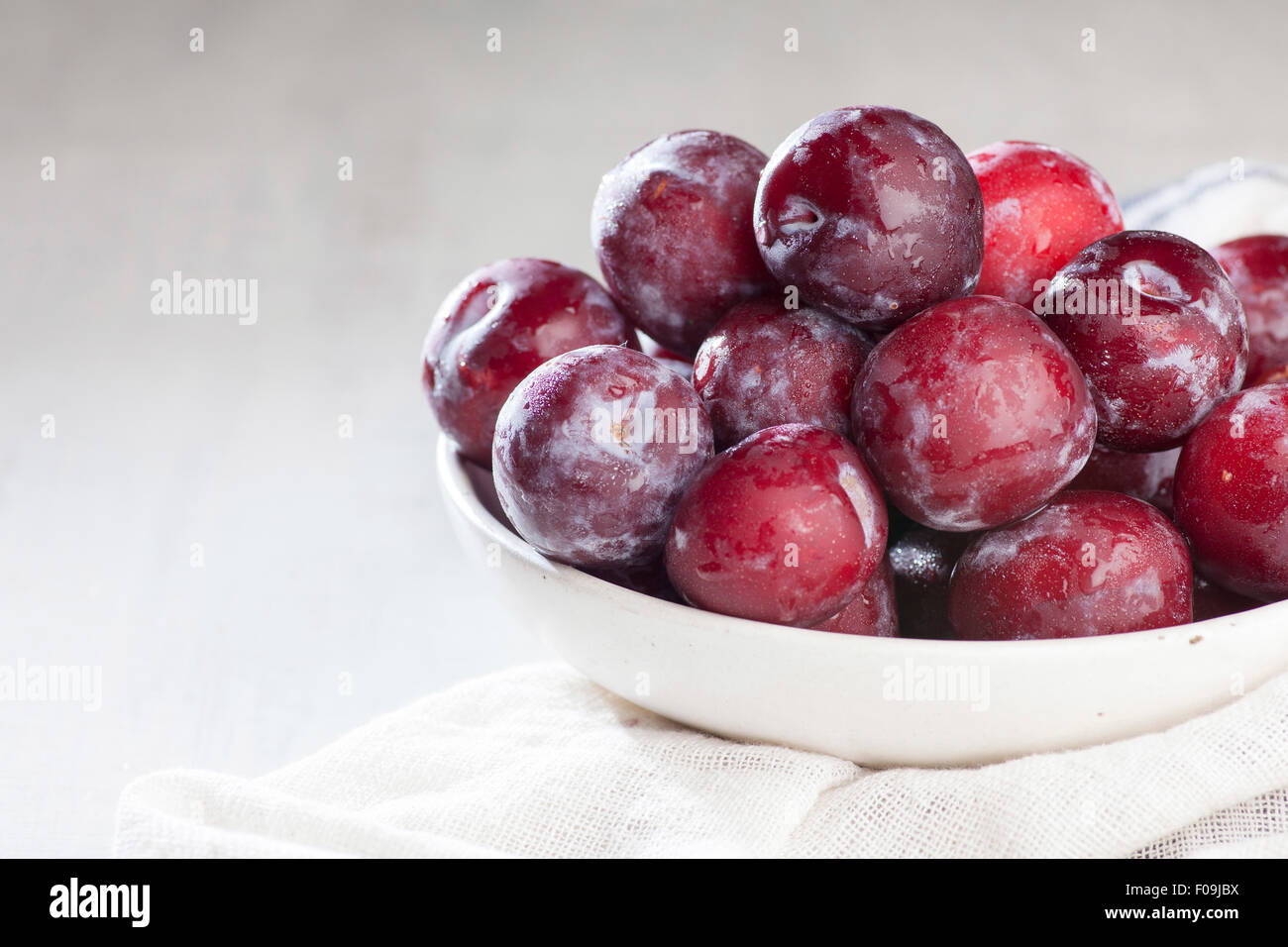 Washed Ripe Plums on white rustic background Stock Photo