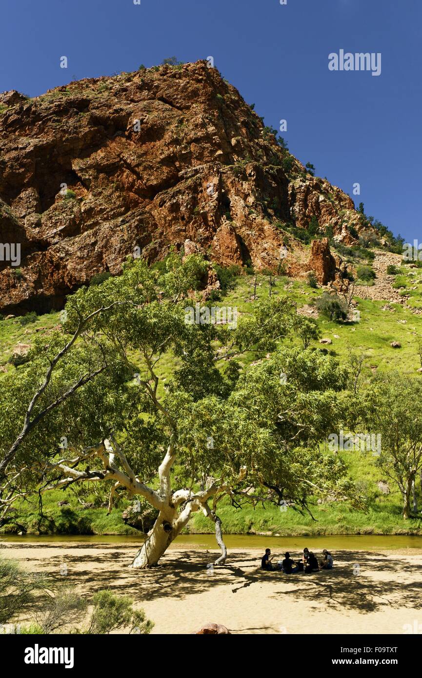 Hikers sittng under tree in front of Simpson's Gap, Larapinta Trail, Australia Stock Photo