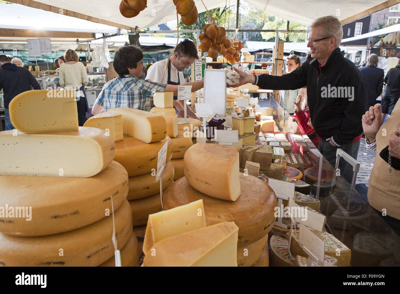 Shopkeeper attending customers at cheese stand in Noordermarkt, Jordaan, Amsterdam Stock Photo