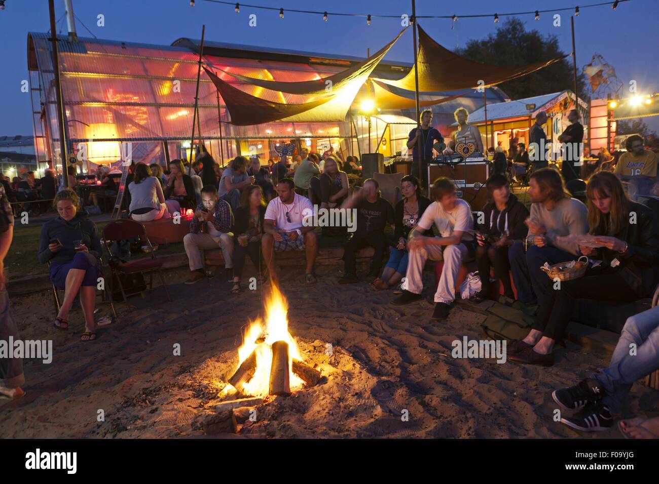 People around campfire at Noorderlicht Cafe, NDSM shipyard, Noord, Amsterdam, Netherlands Stock Photo