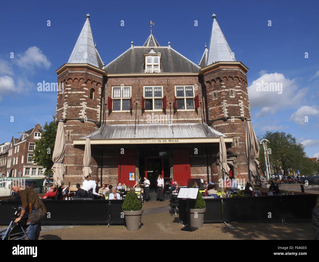 Tourists standing and cycling outside Waag monument in Nieuwmarkt, Amsterdam, Netherlands Stock Photo