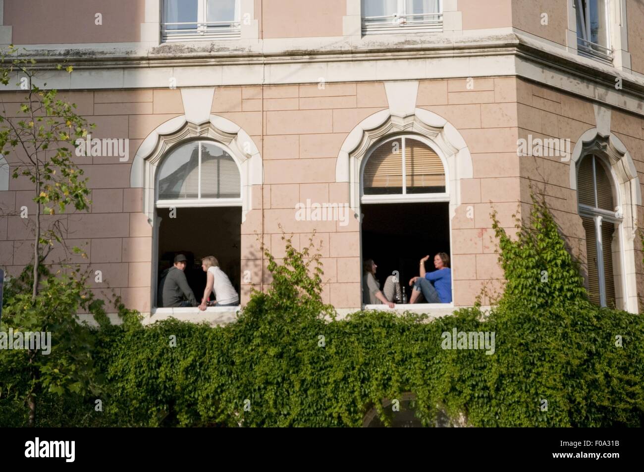 People sitting at window of building in Volksgarten street, Southtown, Cologne, Germany Stock Photo