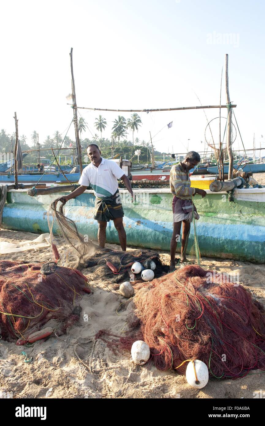 Multi-colored fishing nets drying in the sun next to small fishing boat on  Nilaveli beach in Trincomalee Sri Lanka Asia Stock Photo - Alamy