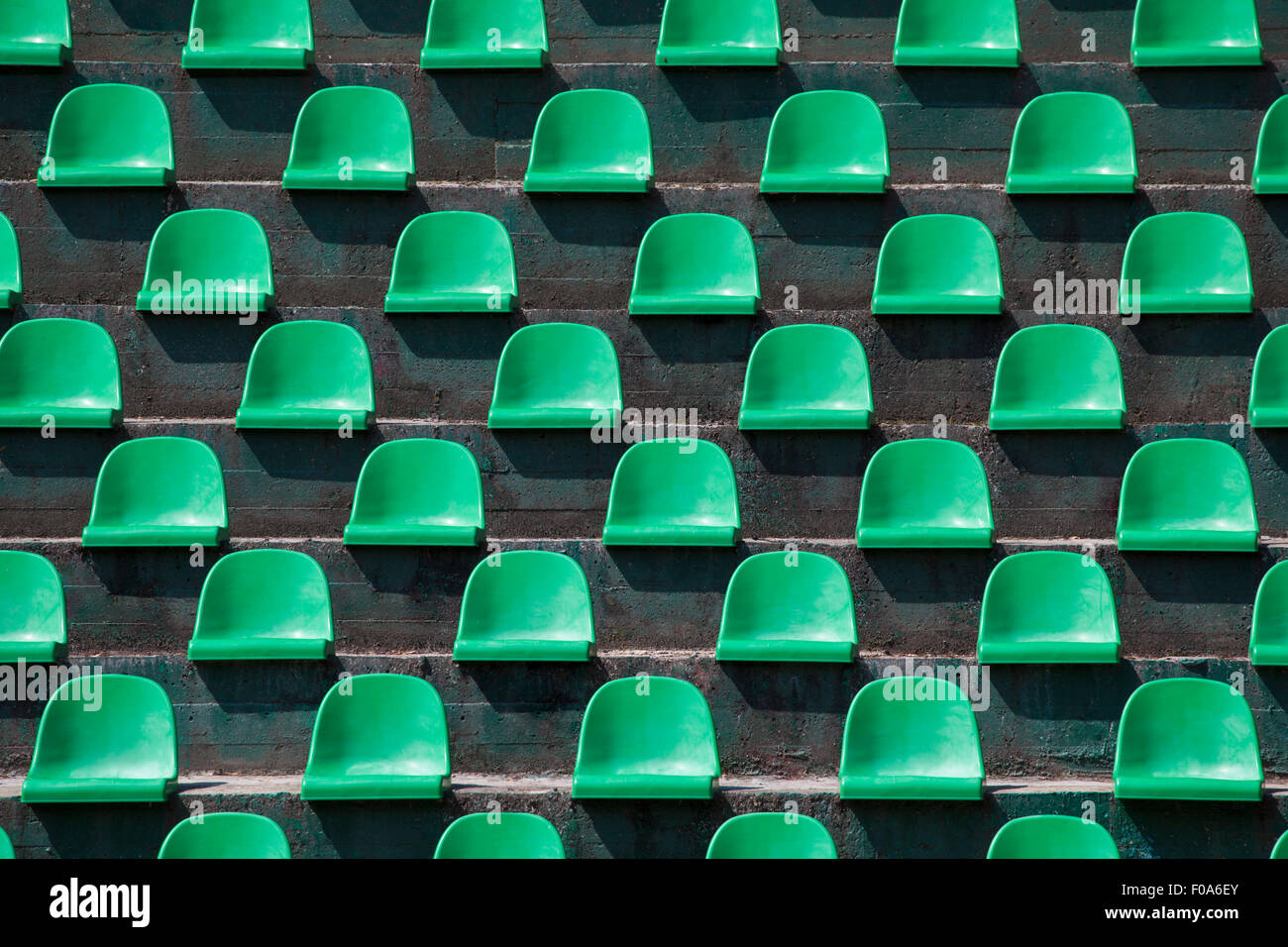 Image of green plastic stadium seats in rows. The seats are filled the frame as background. This is a day shot of an empty stadi Stock Photo