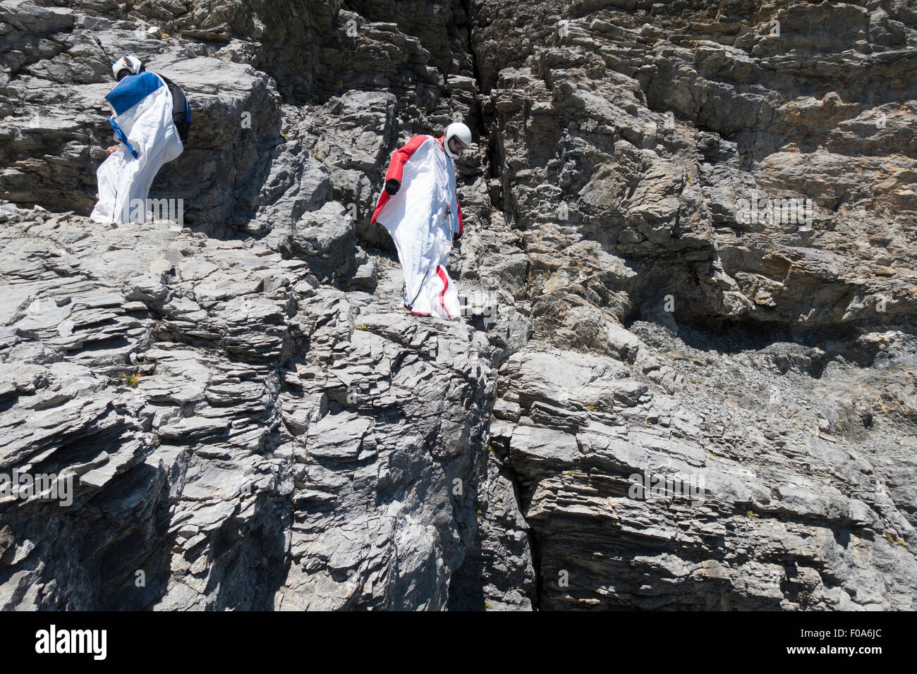 Wingsuit BASE jumpers are getting ready to jump off a cliff and checking the altitude by facing downward & adjusting his wings. Stock Photo